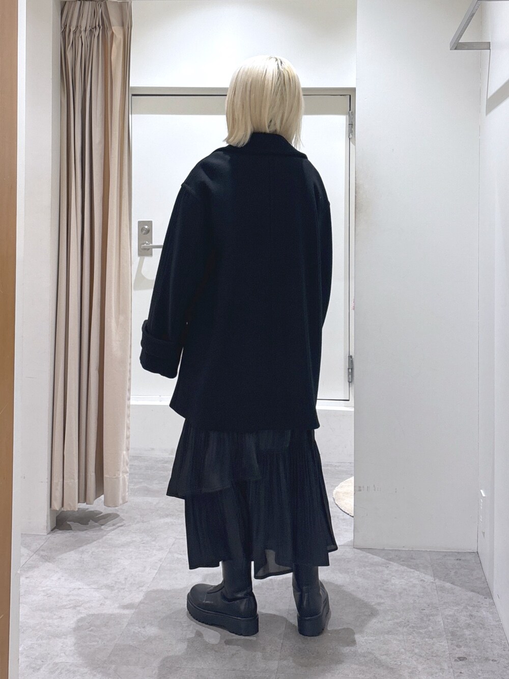 ブラック系のピーコート、ブラック系のショルダーバッグ、ブラック系のスカートを着用したレディースの冬コーディネートの4枚目の写真