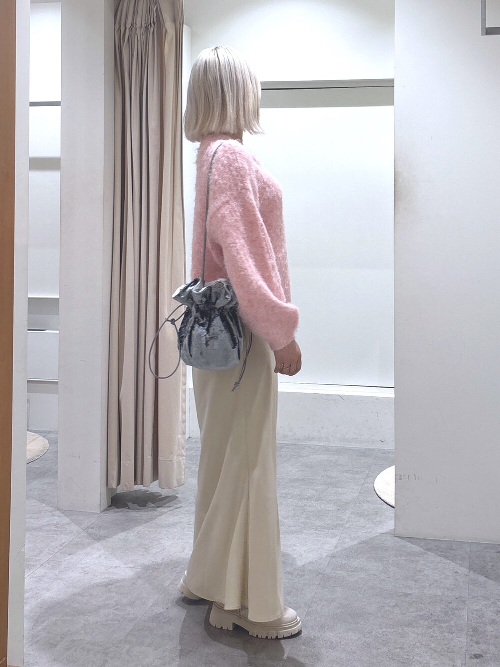 ピンク系のニット/セーター、ベージュ系のスカート、ホワイト系のブーツを着用したレディースの冬コーディネートの3枚目の写真