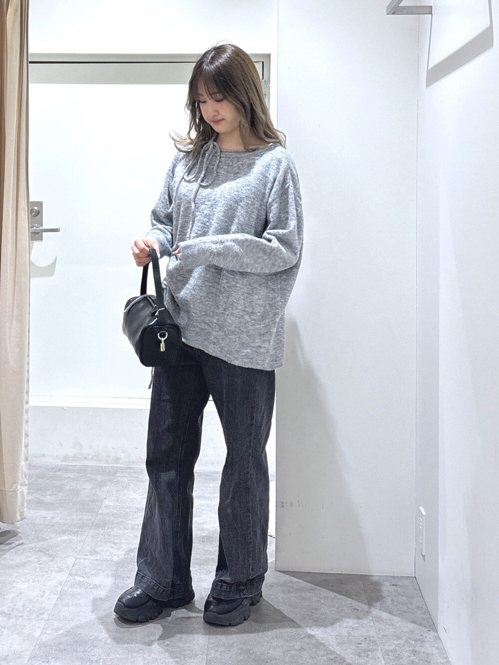 グレー系のニット/セーター、ブラック系のデニムパンツ、ブラック系のハンドバッグを着用したレディースの冬コーディネートの2枚目の写真