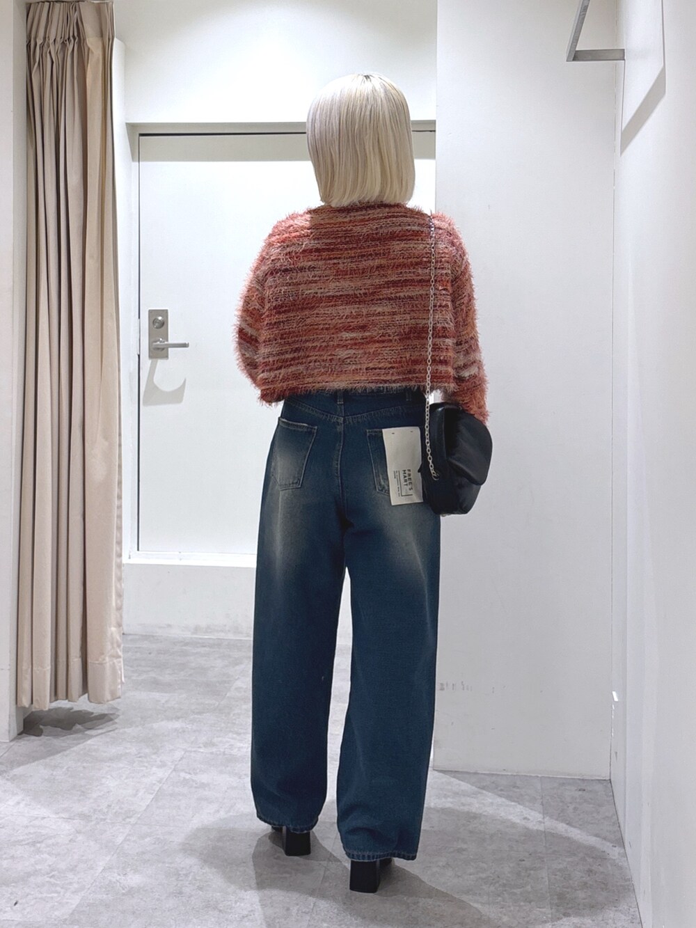 ブルー系のデニムパンツ、レッド系のニット/セーター、ホワイト系のTシャツ/カットソーを着用したレディースの冬コーディネートの4枚目の写真