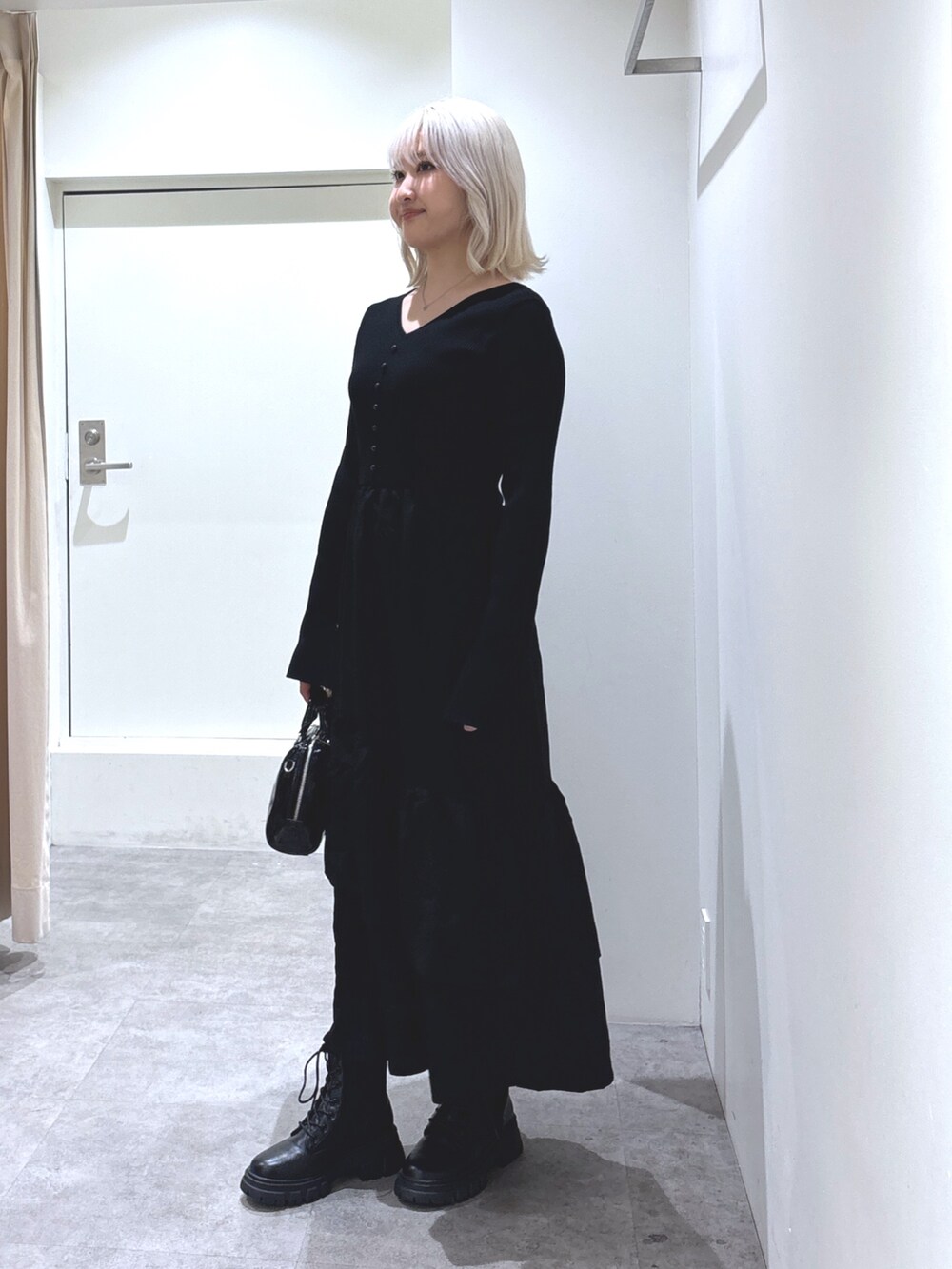 ブラック系のワンピース、ブラック系のブーツ、ブラック系のショルダーバッグを着用したレディースの冬コーディネートの3枚目の写真