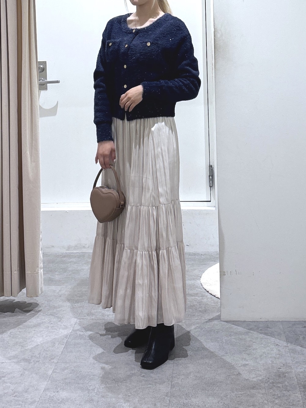 ブルー系のニット/セーター、ホワイト系のスカート、ブラウン系のショルダーバッグを着用したレディースの冬コーディネートの2枚目の写真