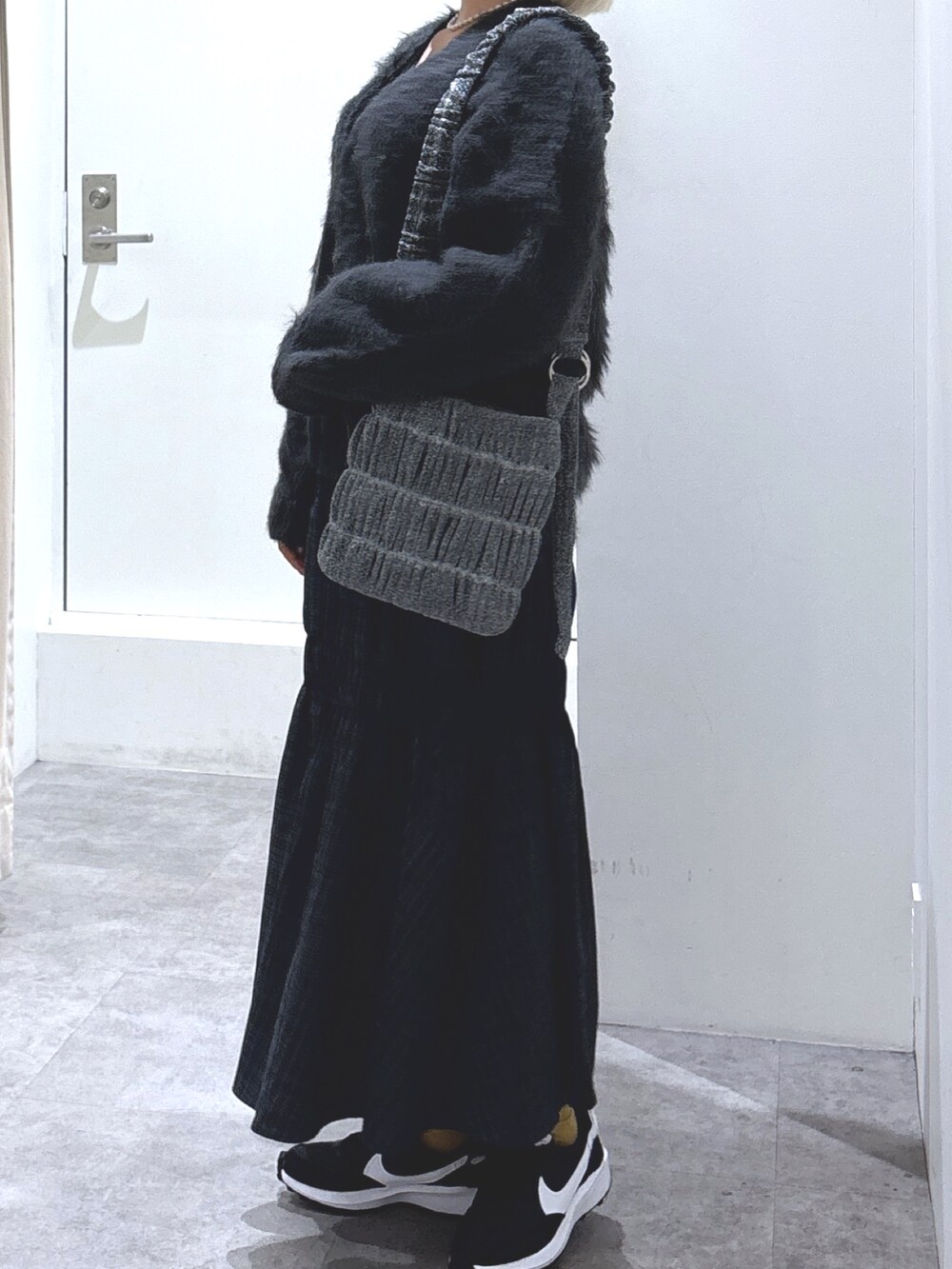 グレー系のスカート、グレー系のカーディガン/ボレロ、ブラック系のキャミソールを着用したレディースの冬コーディネートの3枚目の写真