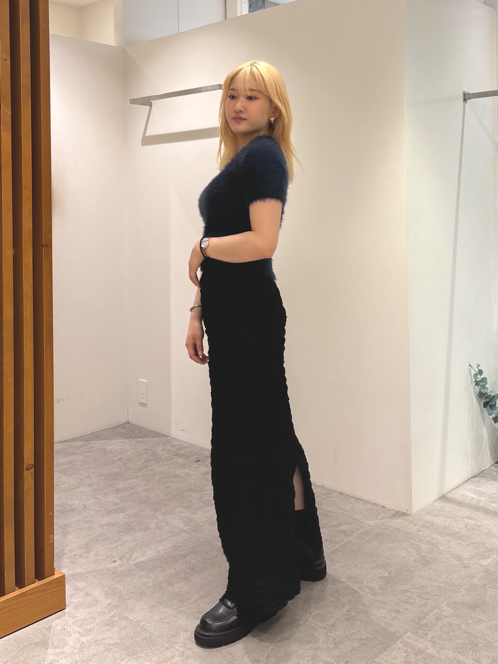 ブルー系のニット/セーター、ブラック系のスカート、ブラック系のブーツを着用したレディースの秋コーディネートの2枚目の写真