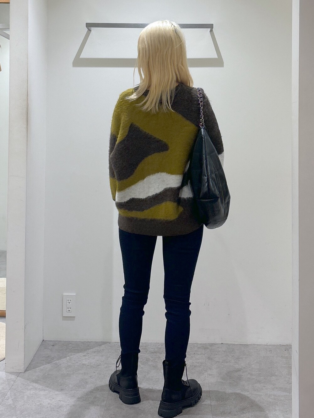 ブラウン系のニット/セーター、ブラック系のデニムパンツ、ブラック系のブーツを着用したレディースの秋コーディネートの4枚目の写真