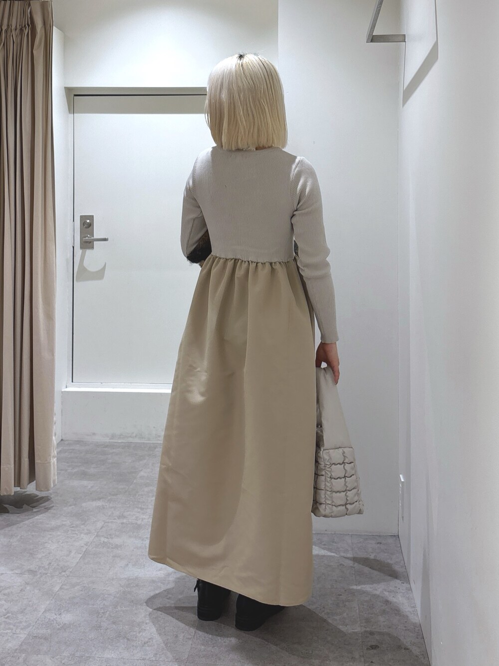 ブラック系のブーツ、ホワイト系のハンドバッグ、グレー系のTシャツ/カットソーを着用したレディースの冬コーディネートの2枚目の写真