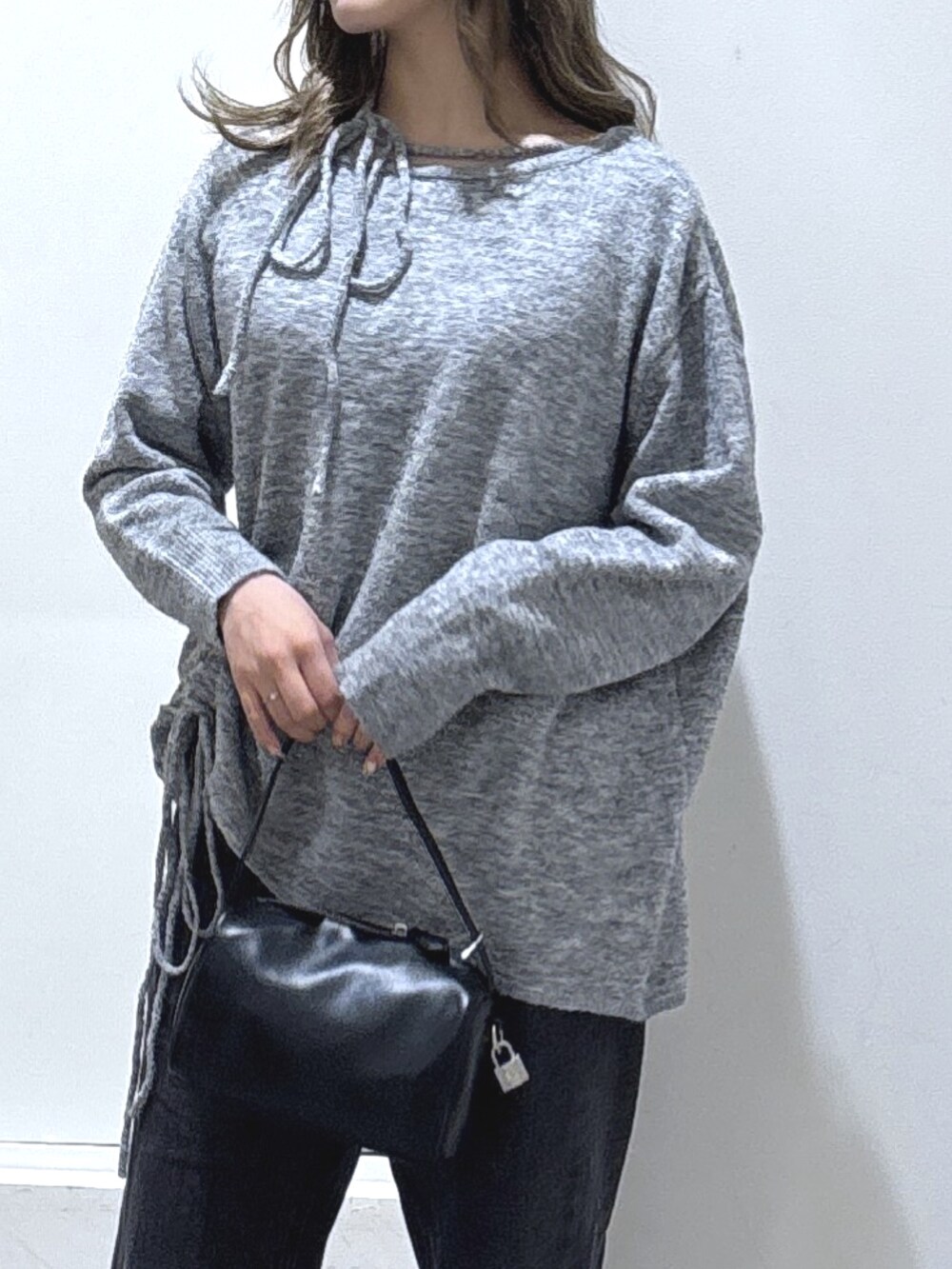 グレー系のニット/セーター、ブラック系のデニムパンツ、ブラック系のハンドバッグを着用したレディースの冬コーディネートの3枚目の写真