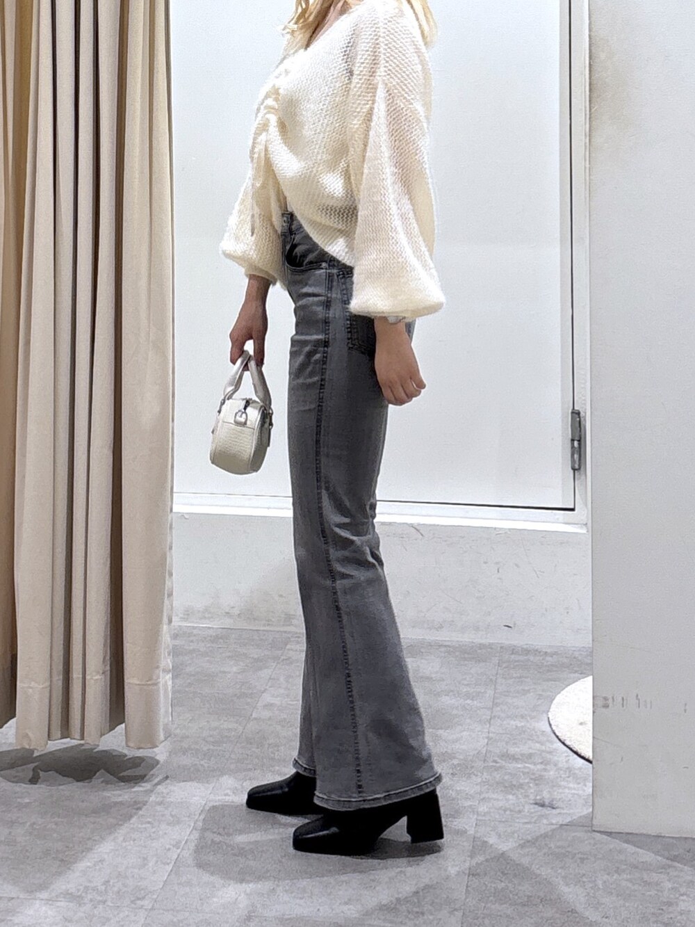 ホワイト系のニット/セーター、ブラック系のデニムパンツを着用したレディースの秋コーディネートの4枚目の写真