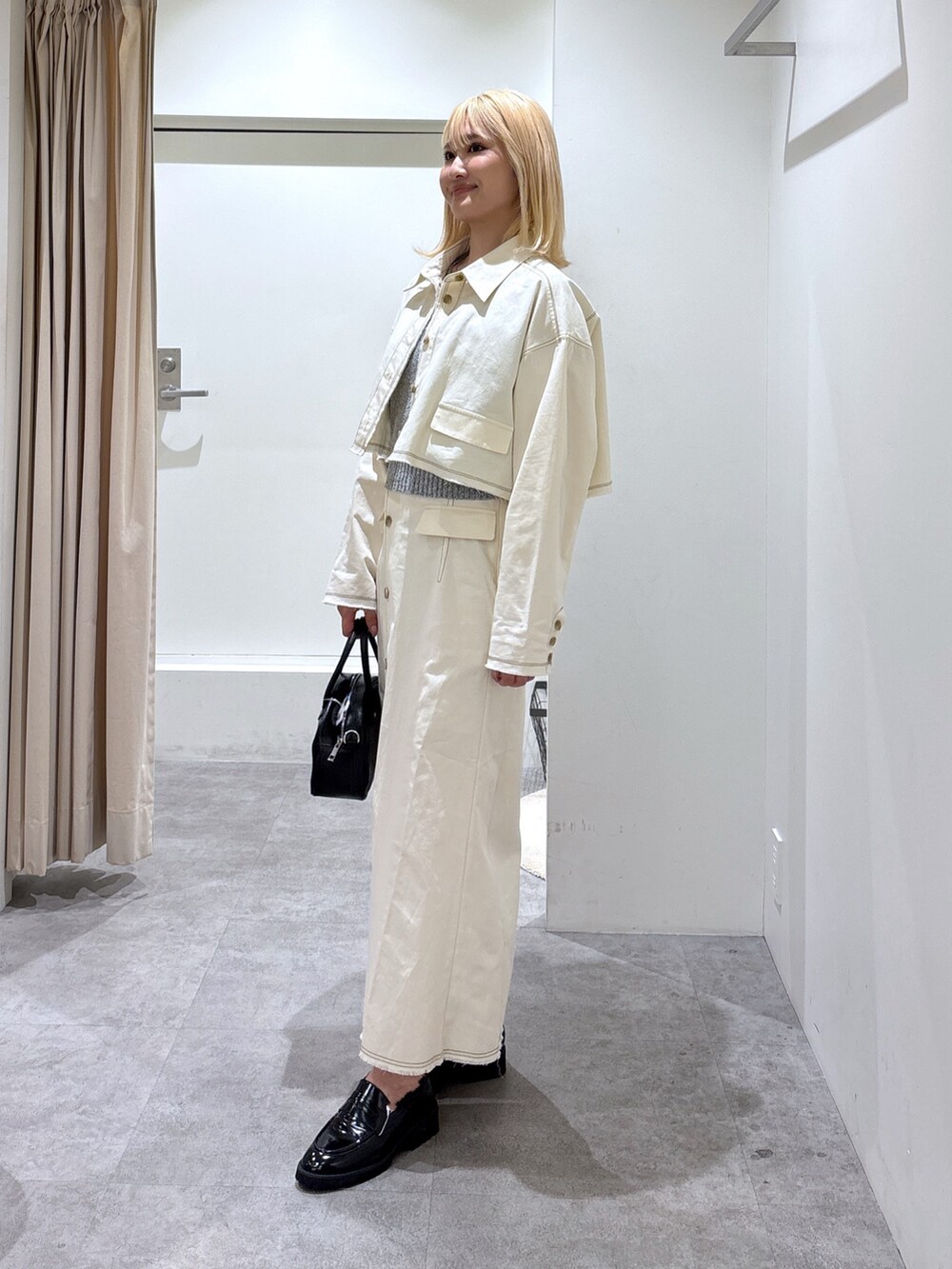 ホワイト系のブルゾン、ホワイト系のスカート、グレー系のベストを着用したレディースの春コーディネートの3枚目の写真