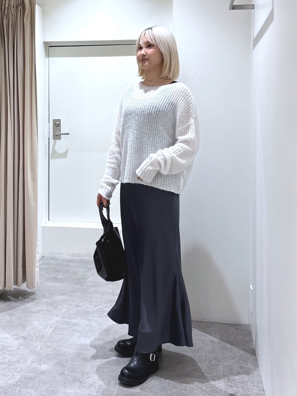 ホワイト系のニット/セーター、ブラック系のスカート、ブラック系のハンドバッグを着用したレディースの冬コーディネートの2枚目の写真