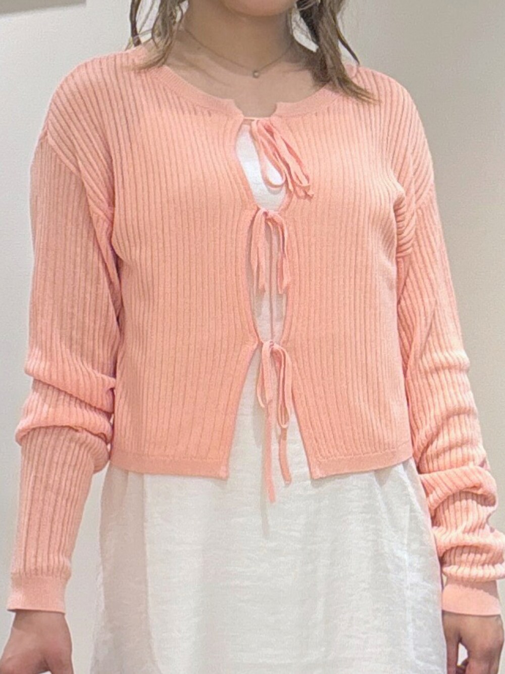 ピンク系のカーディガン/ボレロ、ホワイト系のワンピース、ブラック系のショルダーバッグを着用したレディースの夏コーディネートの2枚目の写真