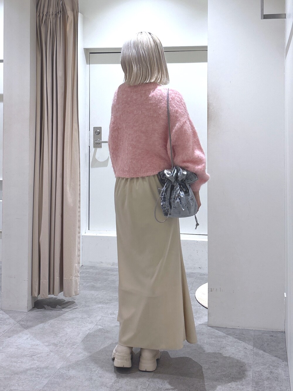 ピンク系のニット/セーター、ベージュ系のスカート、ホワイト系のブーツを着用したレディースの冬コーディネートの4枚目の写真