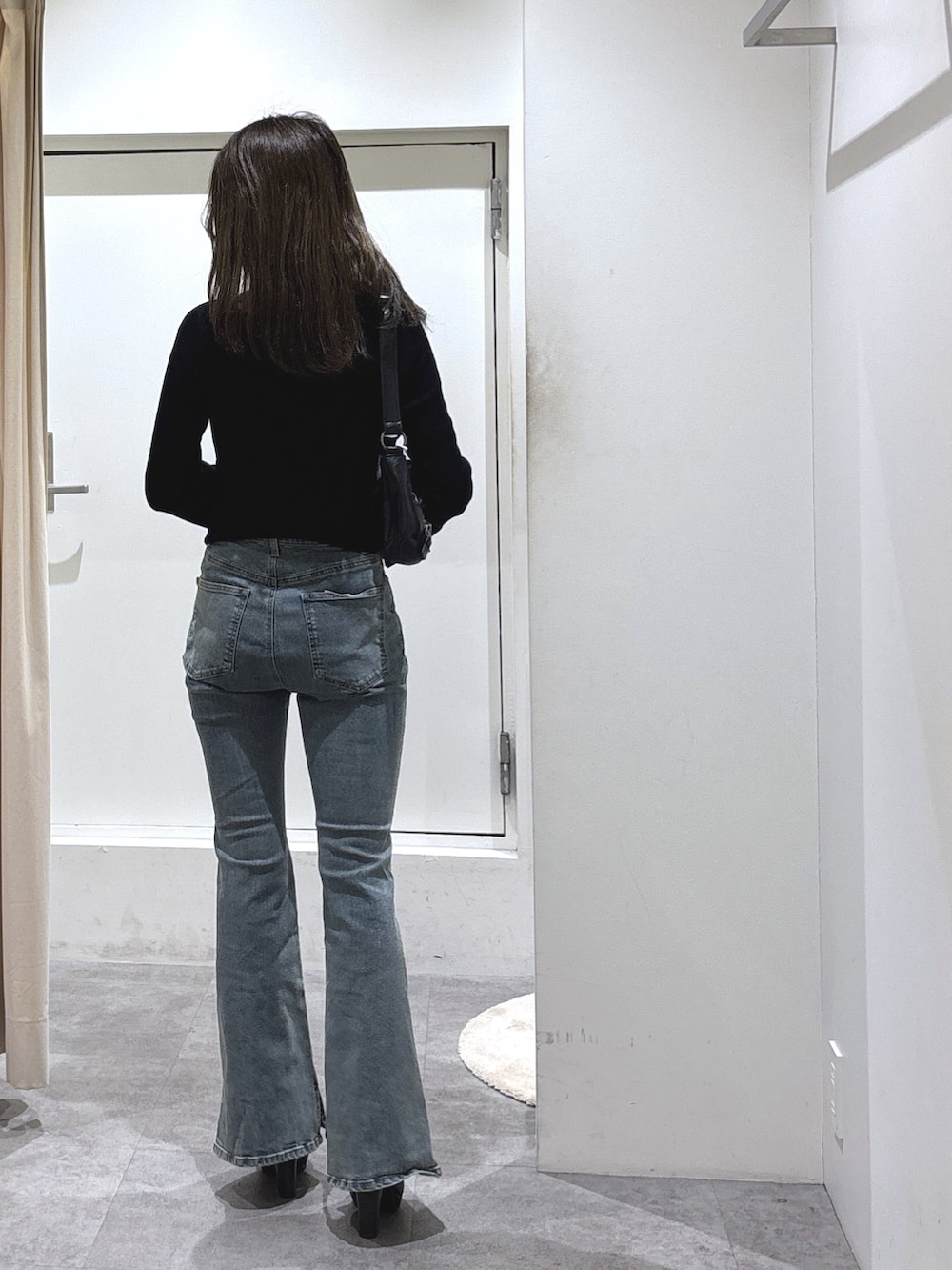 ブラック系のニット/セーター、ブルー系のデニムパンツ、ブラック系のブーツを着用したレディースの冬コーディネートの3枚目の写真