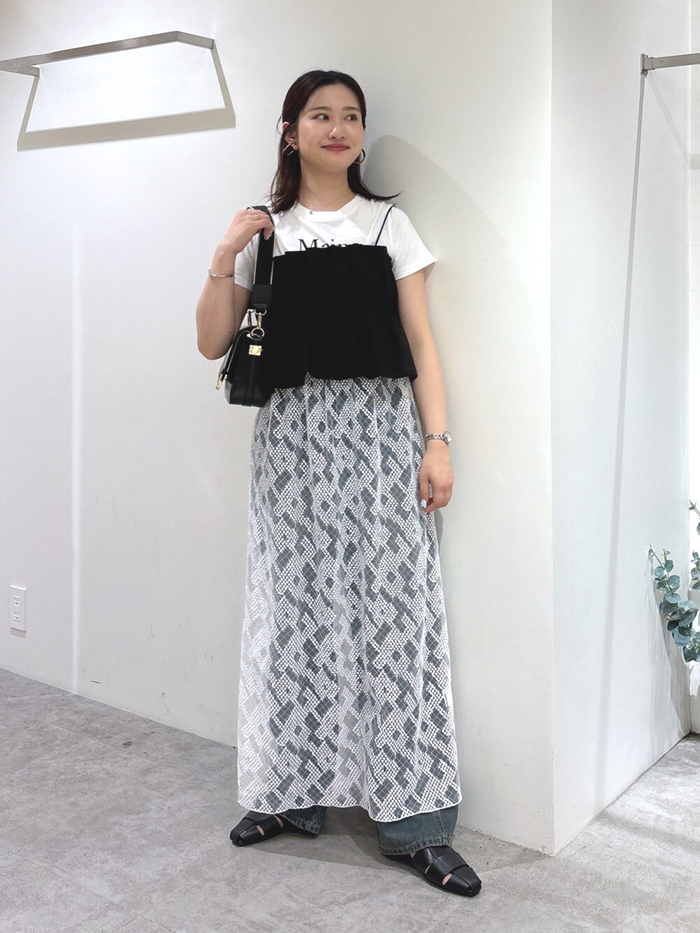 ブラック系のショルダーバッグ、ブラック系のシャツ/ブラウス、ブルー系のデニムパンツを着用したレディースの夏コーディネートの2枚目の写真