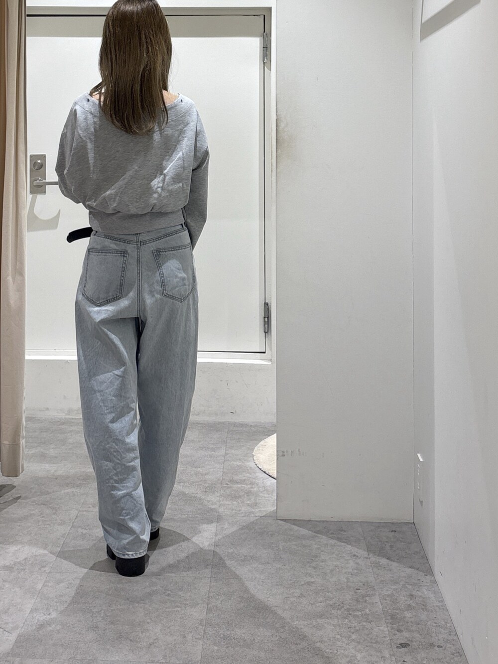 グレー系のスウェット、ブルー系のデニムパンツ、ブラウン系のブーツを着用したレディースの冬コーディネートの4枚目の写真