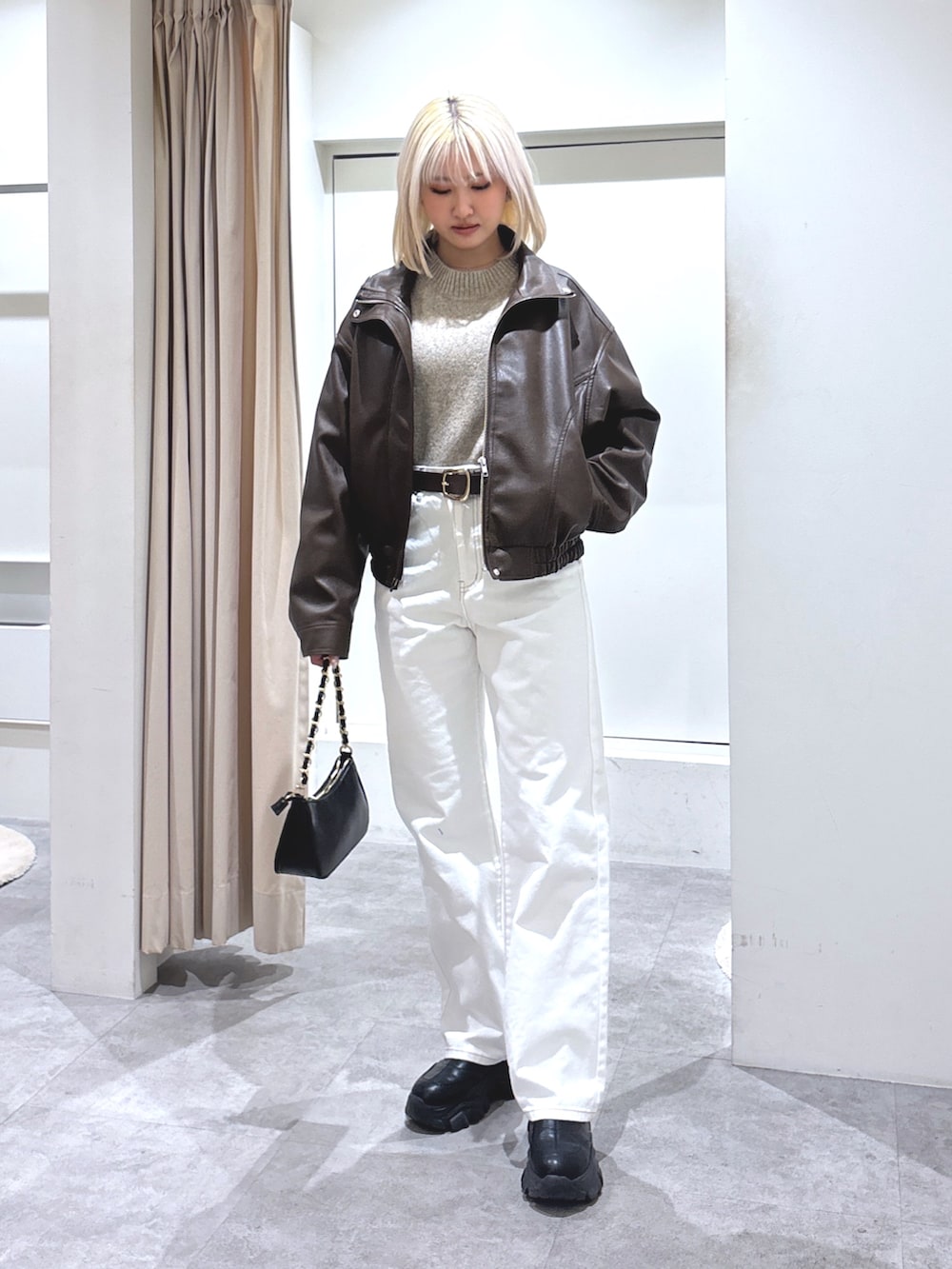 ブラウン系のブルゾン、ベージュ系のニット/セーター、ホワイト系のデニムパンツを着用したレディースの冬コーディネートの2枚目の写真