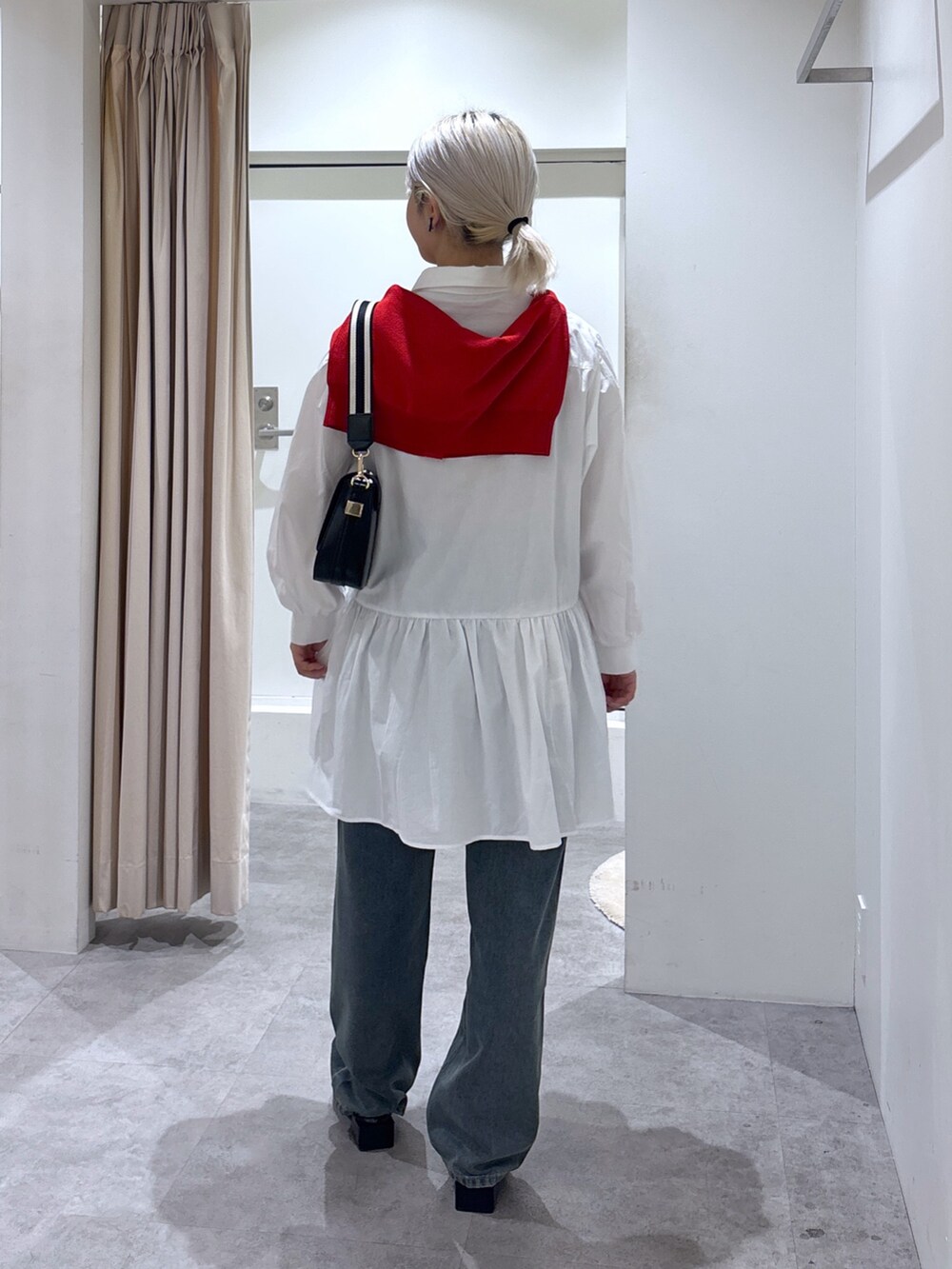 ブルー系のデニムパンツ、レッド系のカーディガン/ボレロ、ホワイト系のワンピースを着用したレディースの春コーディネートの4枚目の写真