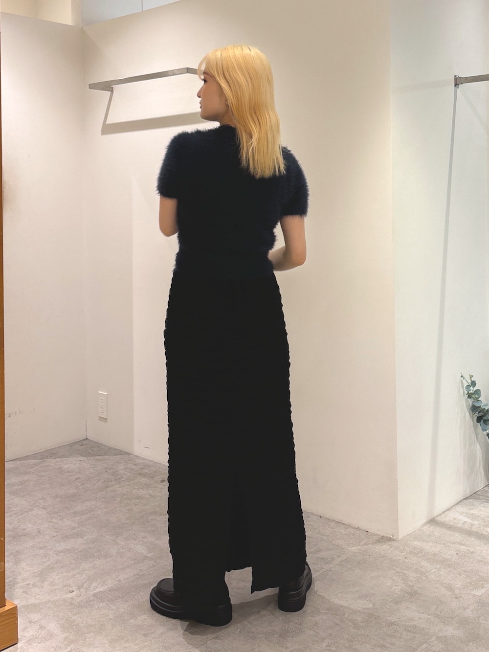 ブルー系のニット/セーター、ブラック系のスカート、ブラック系のブーツを着用したレディースの秋コーディネートの5枚目の写真