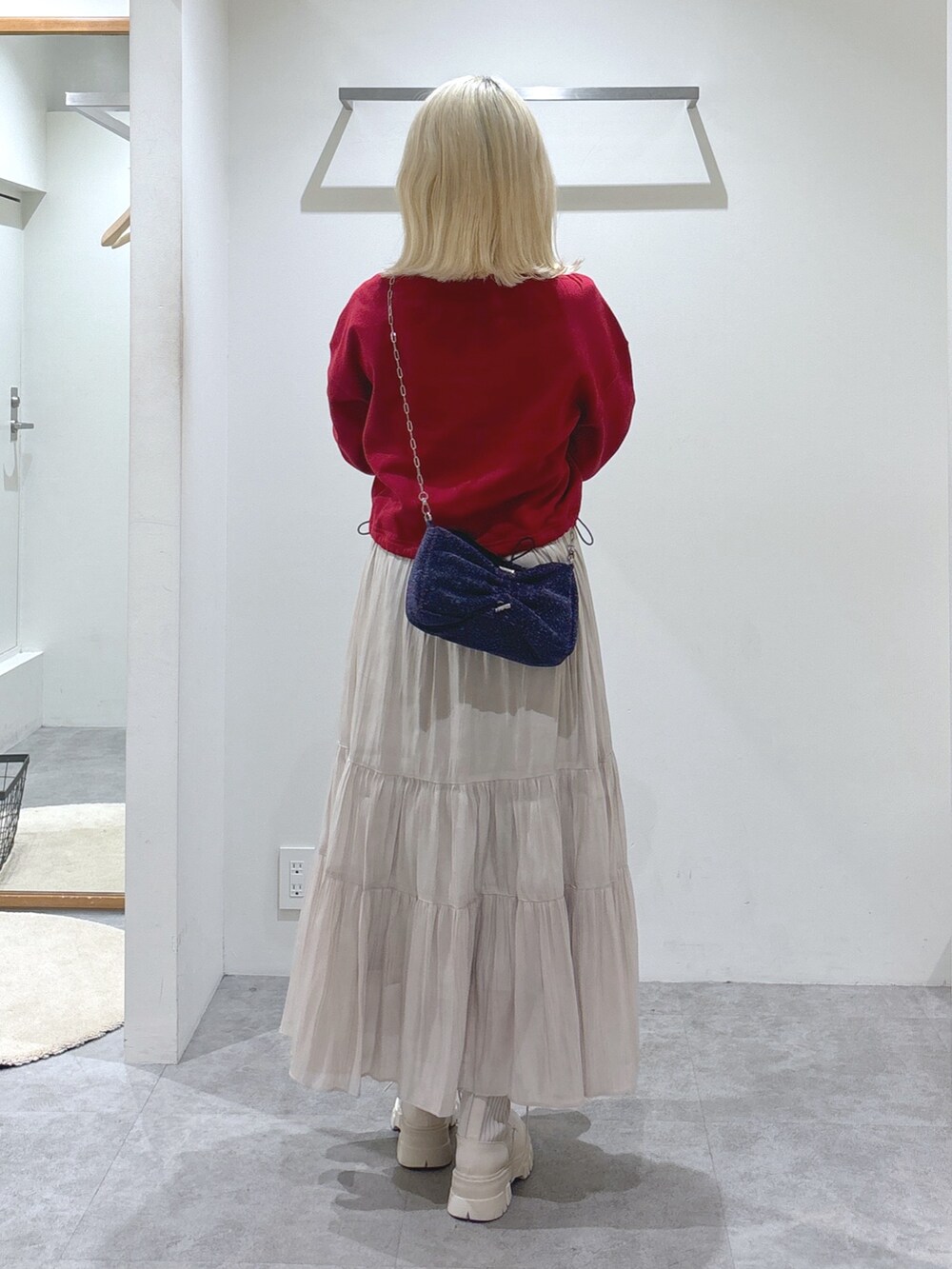 レッド系のTシャツ/カットソー、ホワイト系のスカート、ホワイト系のブーツを着用したレディースの秋コーディネートの5枚目の写真
