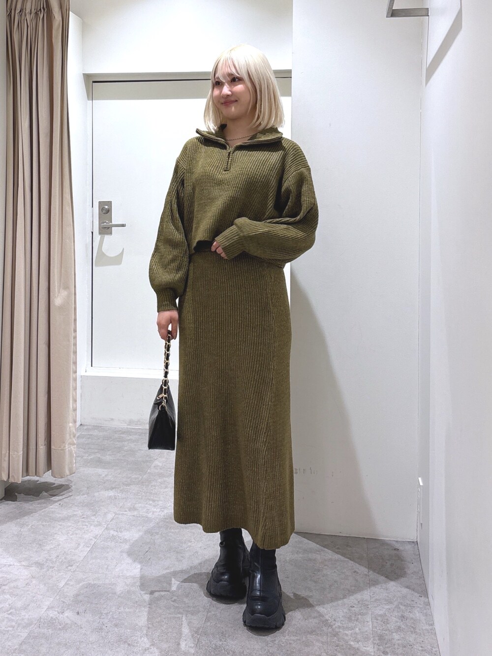 グリーン系のワンピース、ブラック系のトートバッグを着用したレディースの冬コーディネートの2枚目の写真