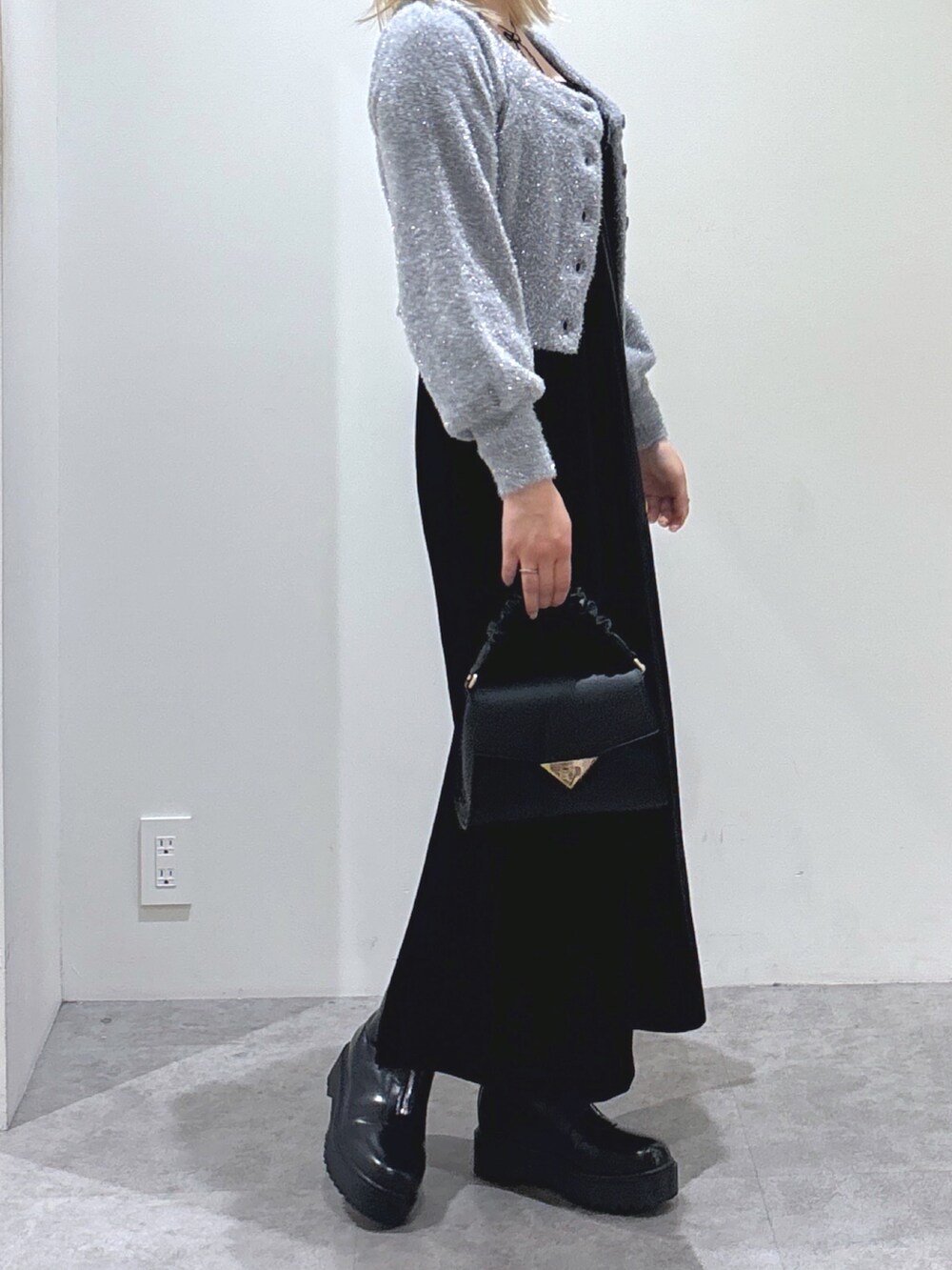 グレー系のカーディガン/ボレロ、ブラック系のワンピース、ブラック系のブーツを着用したレディースの秋コーディネートの2枚目の写真