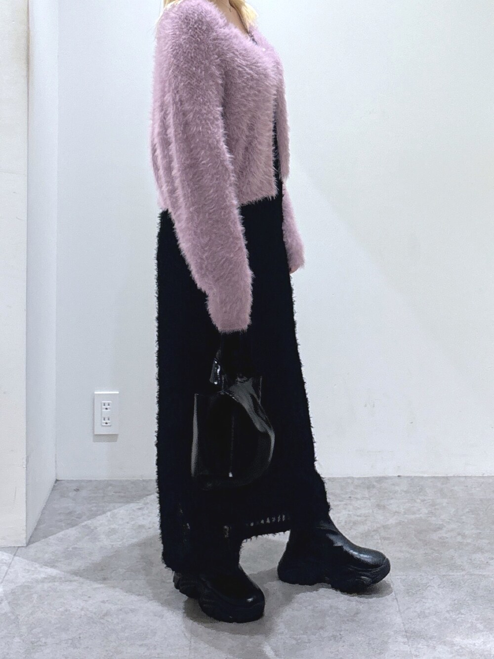 パープル系のカーディガン/ボレロ、ブラック系のワンピース、ブラック系のハンドバッグを着用したレディースの秋コーディネートの2枚目の写真
