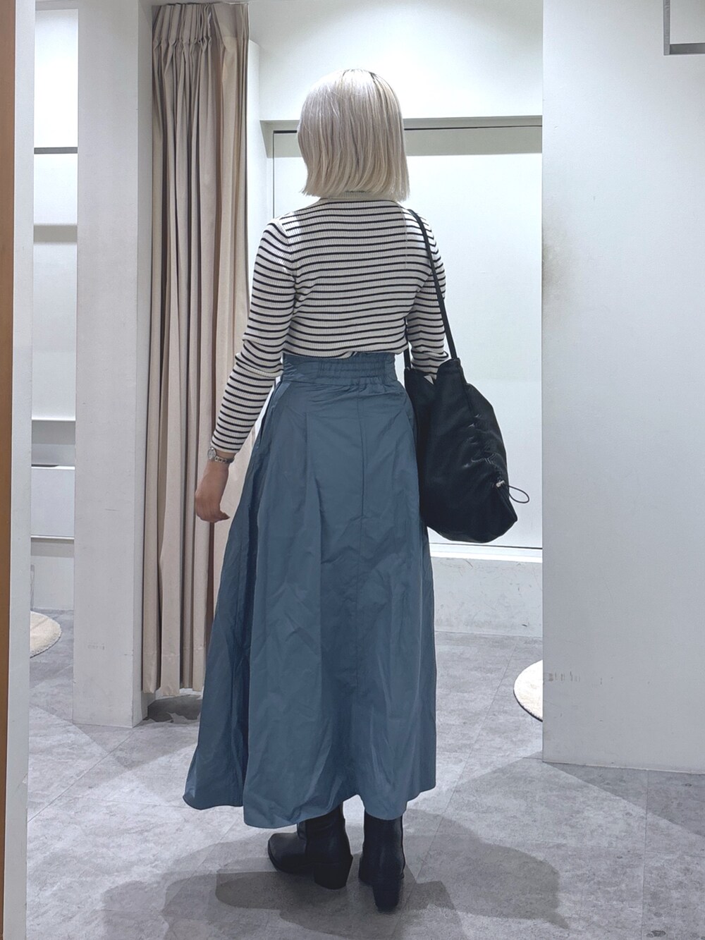 ホワイト系のニット/セーター、ブルー系のスカート、ブラック系のトートバッグを着用したレディースの冬コーディネートの3枚目の写真