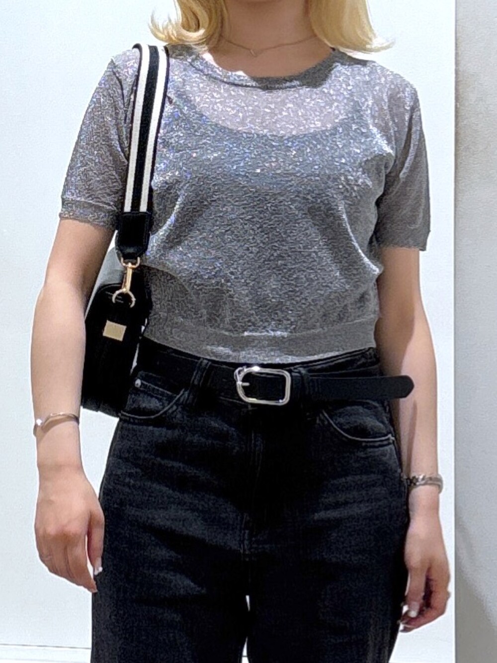 シルバー系のニット/セーター、ブラック系のデニムパンツを着用したレディースの春コーディネートの2枚目の写真