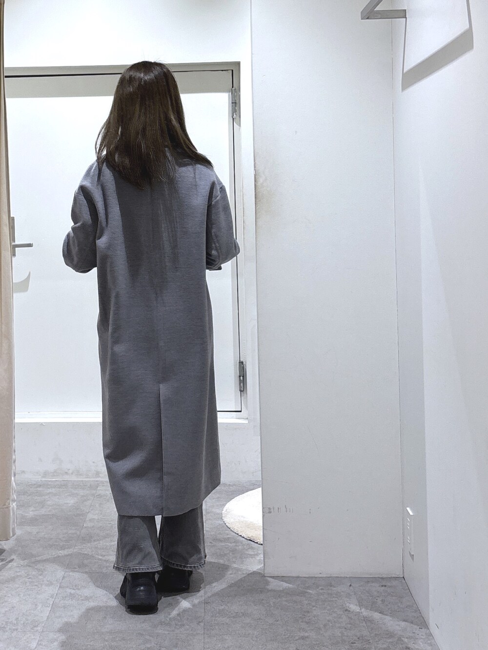 グレー系のチェスターコート、ホワイト系のニット/セーター、ブラック系のデニムパンツを着用したレディースの冬コーディネートの3枚目の写真