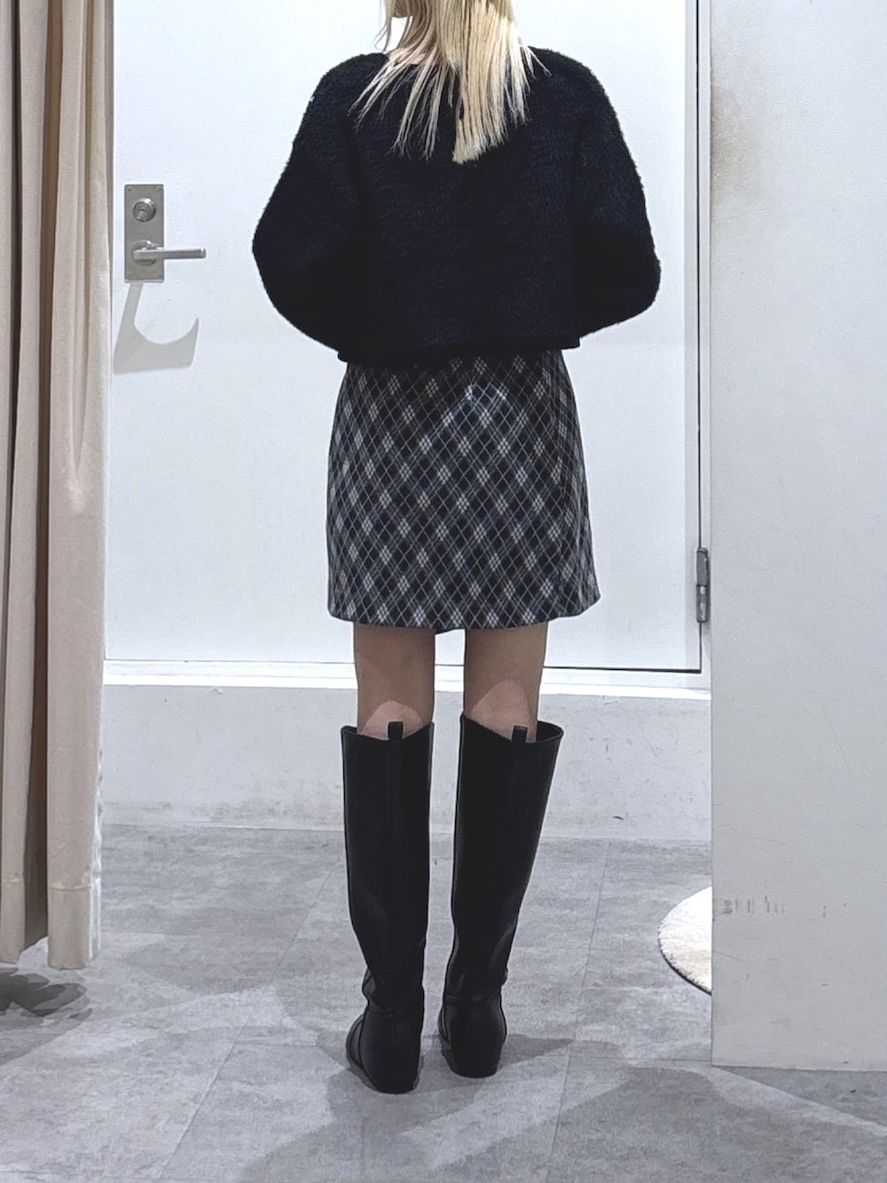 ブラック系のニット/セーター、グレー系のスカート、ブラック系のブーツを着用したレディースの秋コーディネートの3枚目の写真