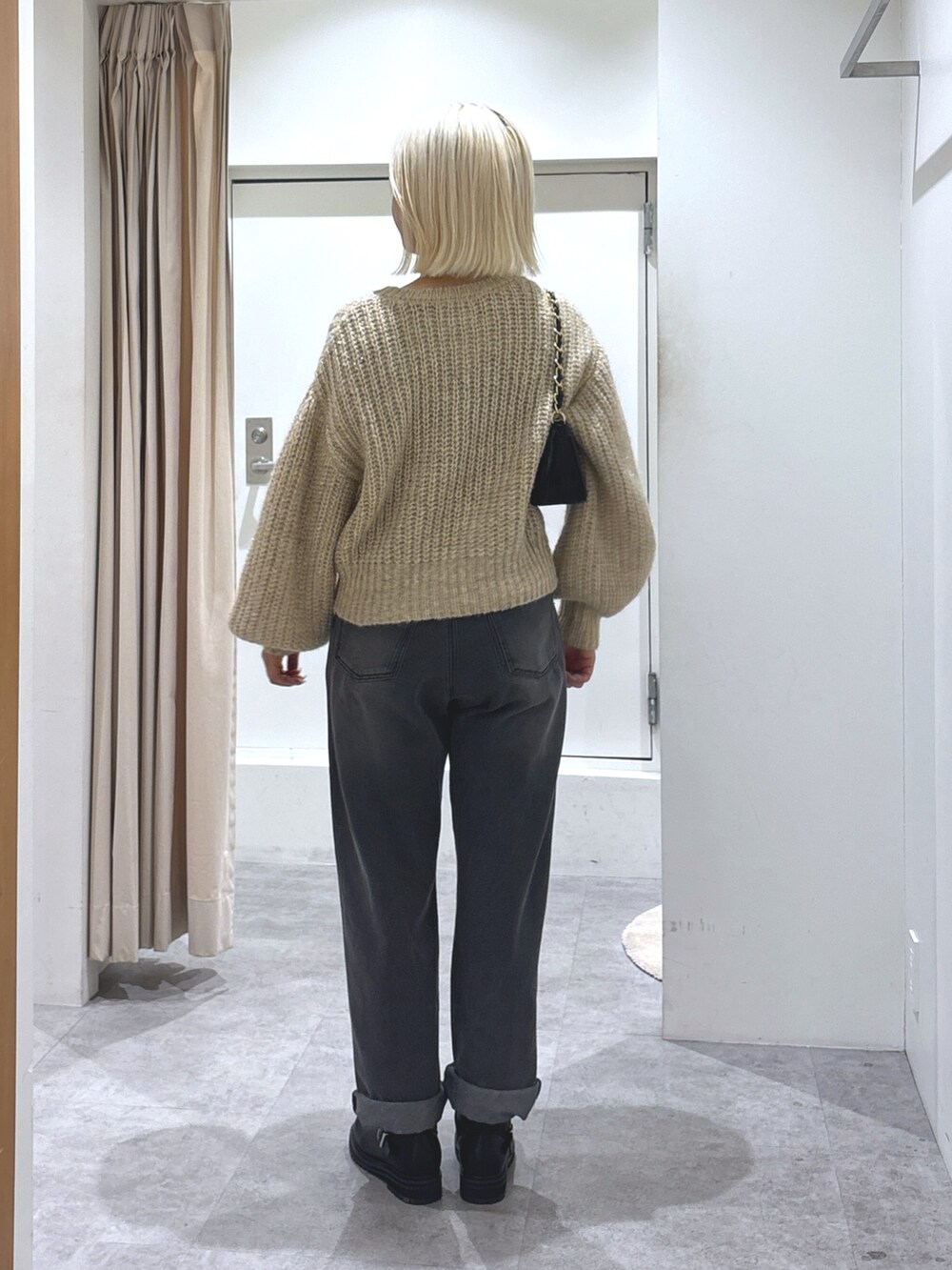 ベージュ系のニット/セーター、ブラック系のデニムパンツ、ブラック系のブーツを着用したレディースの冬コーディネートの4枚目の写真