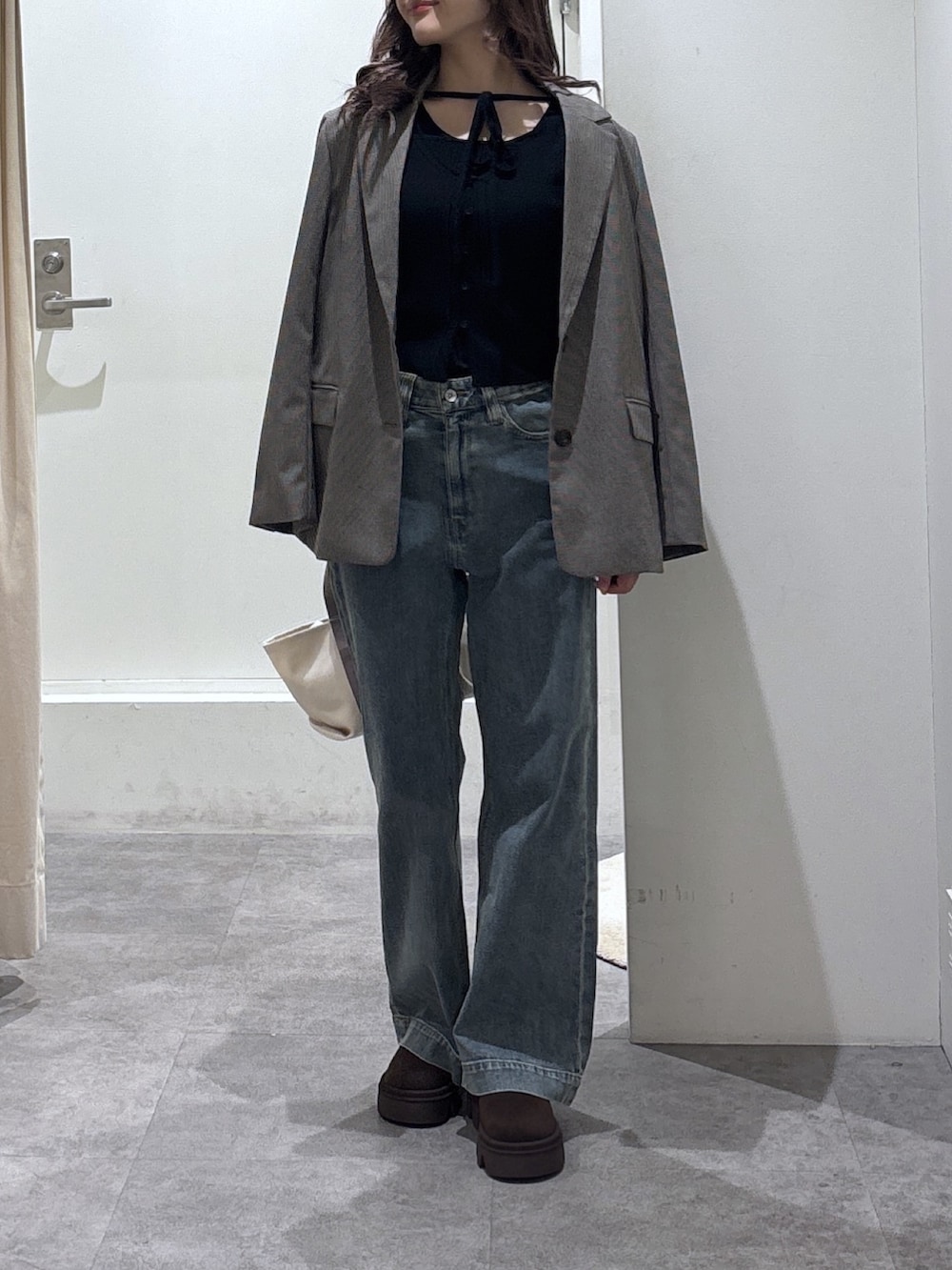 ベージュ系のテーラードジャケット、ブルー系のデニムパンツ、ブラック系のニット/セーターを着用したレディースの冬コーディネートの3枚目の写真