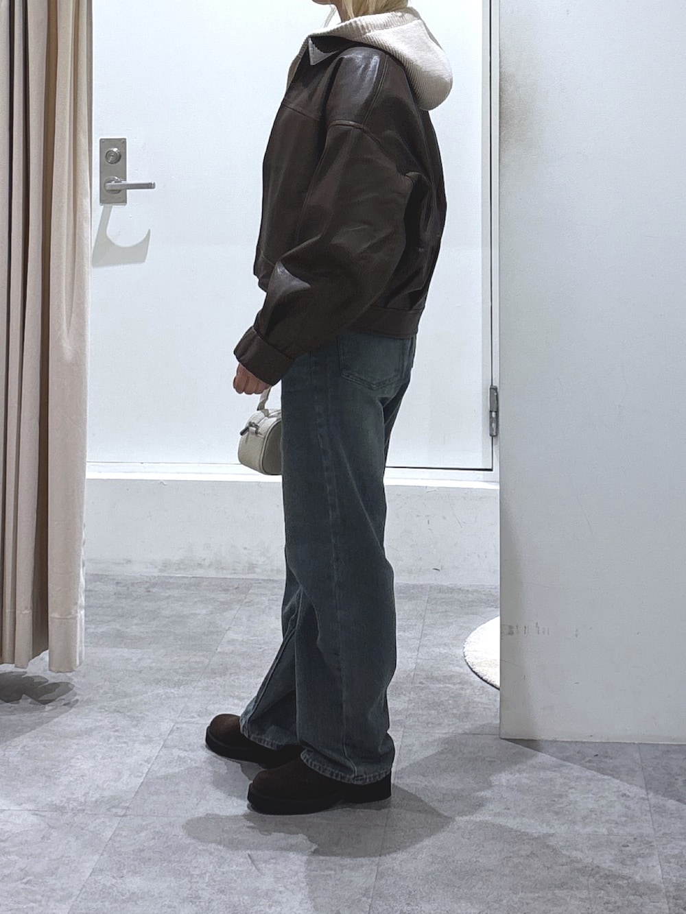 ブラウン系のブルゾン、ベージュ系のニット/セーター、ブルー系のデニムパンツを着用したレディースの秋コーディネートの3枚目の写真