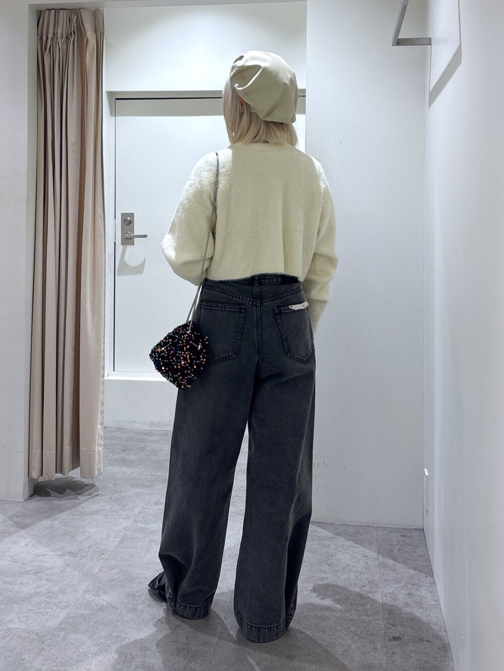 ホワイト系のニット/セーター、ブラック系のデニムパンツ、ホワイト系のTシャツ/カットソーを着用したレディースの冬コーディネートの4枚目の写真