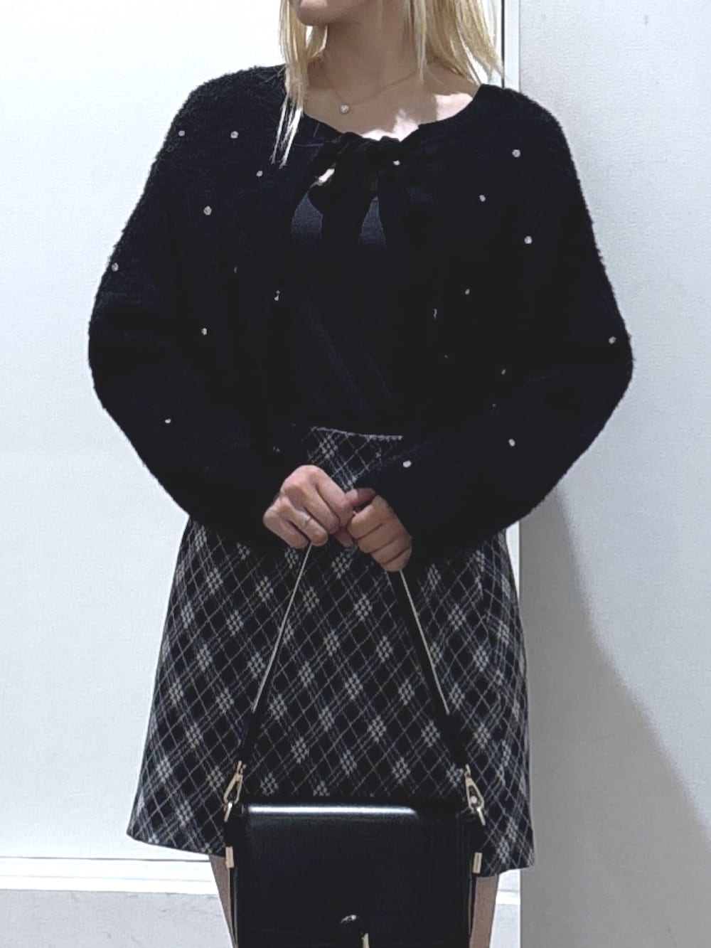 ブラック系のニット/セーター、グレー系のスカート、ブラック系のブーツを着用したレディースの秋コーディネートの2枚目の写真