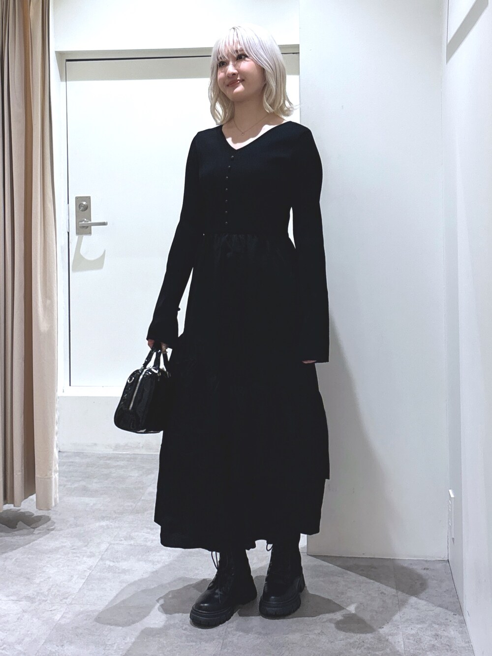 ブラック系のワンピース、ブラック系のブーツ、ブラック系のショルダーバッグを着用したレディースの冬コーディネートの2枚目の写真