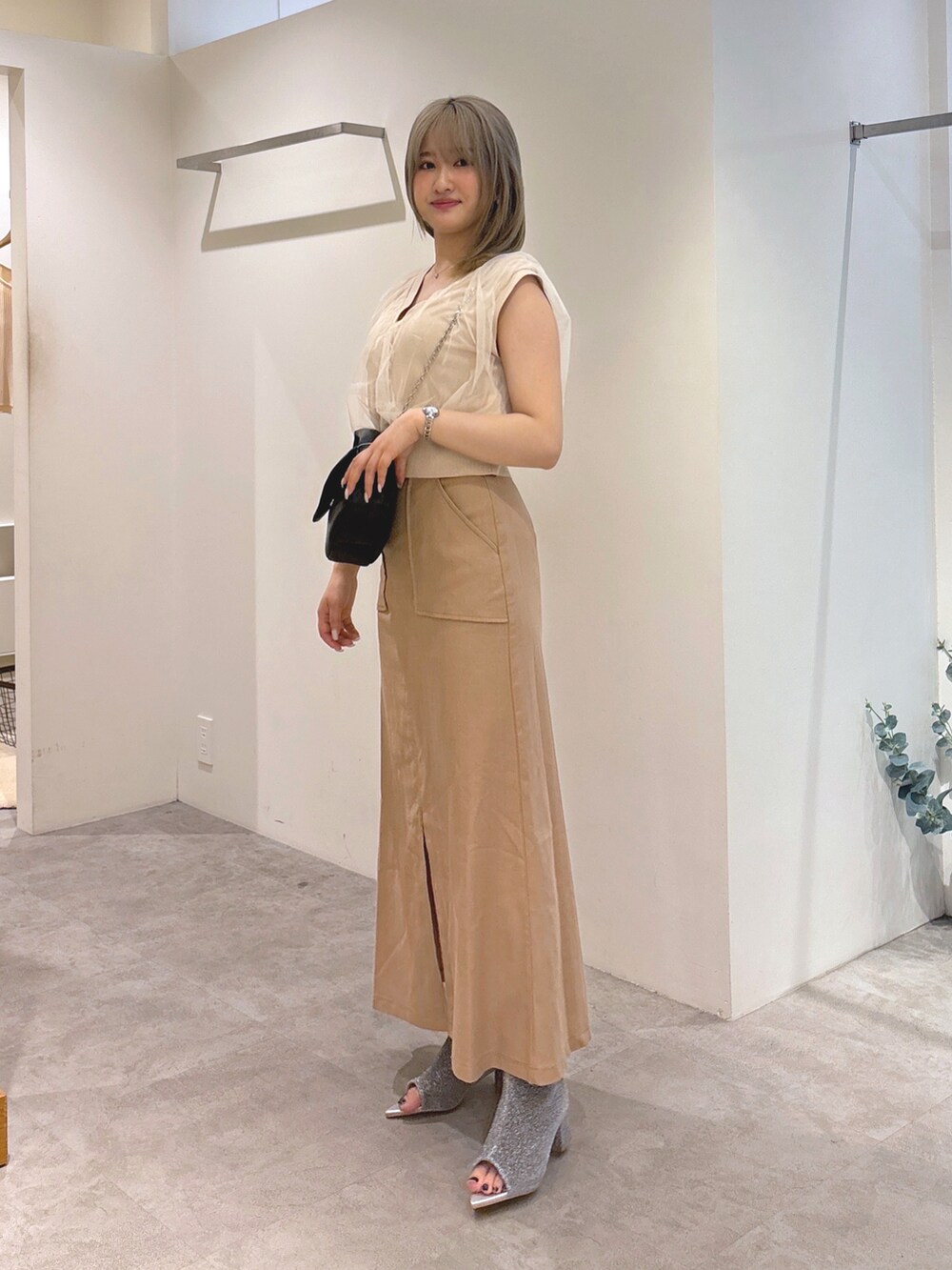 ホワイト系のベスト、ブラウン系のスカート、ブラック系のショルダーバッグを着用したレディースの夏コーディネートの3枚目の写真