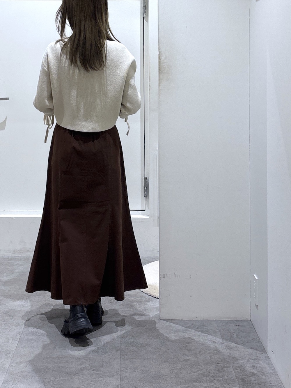 ブラウン系のスカート、ホワイト系のニット/セーター、ホワイト系のショルダーバッグを着用したレディースの冬コーディネートの4枚目の写真