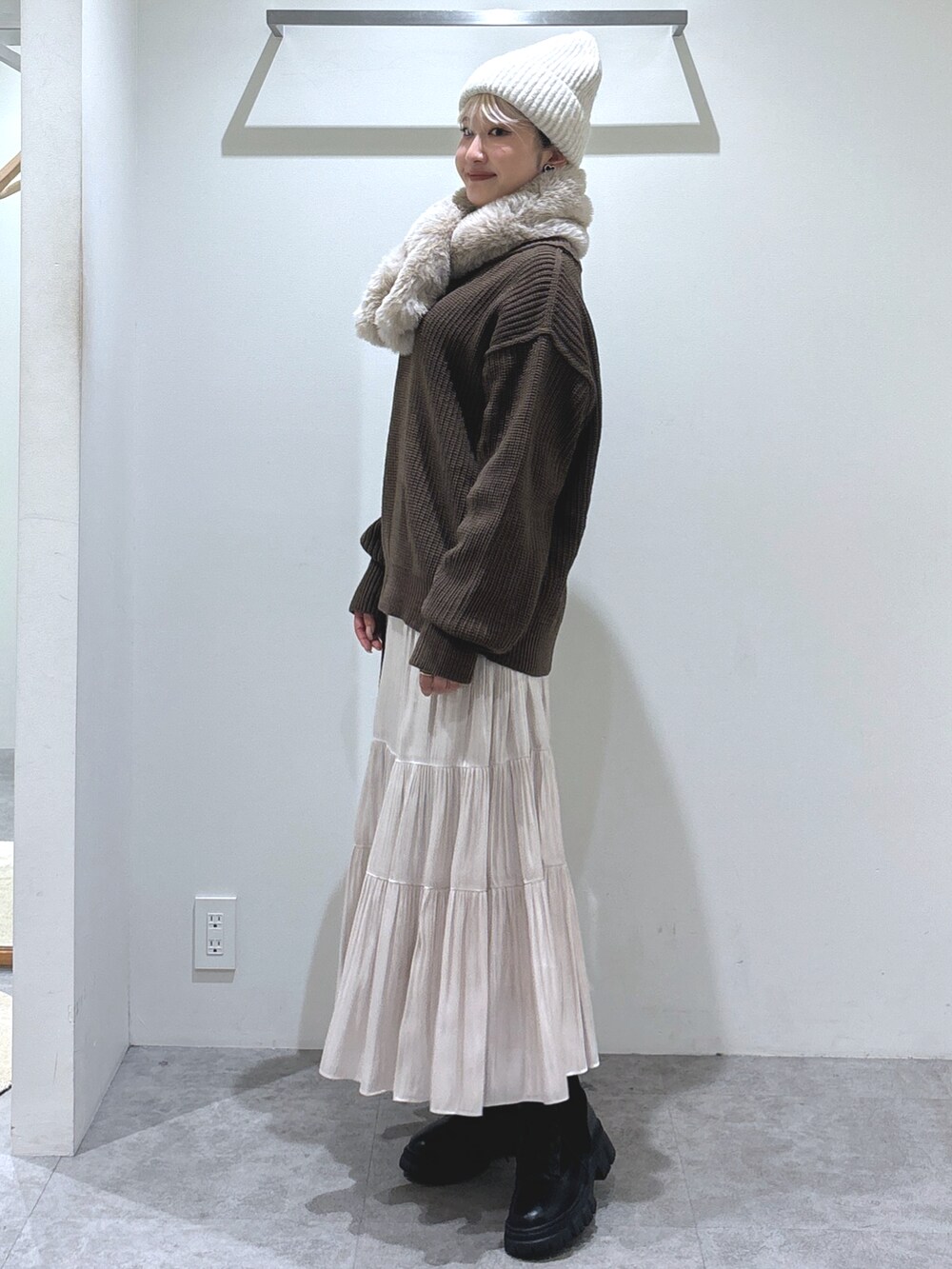 ブラウン系のニット/セーター、ホワイト系のスカート、ブラック系のショルダーバッグを着用したレディースの秋コーディネートの2枚目の写真