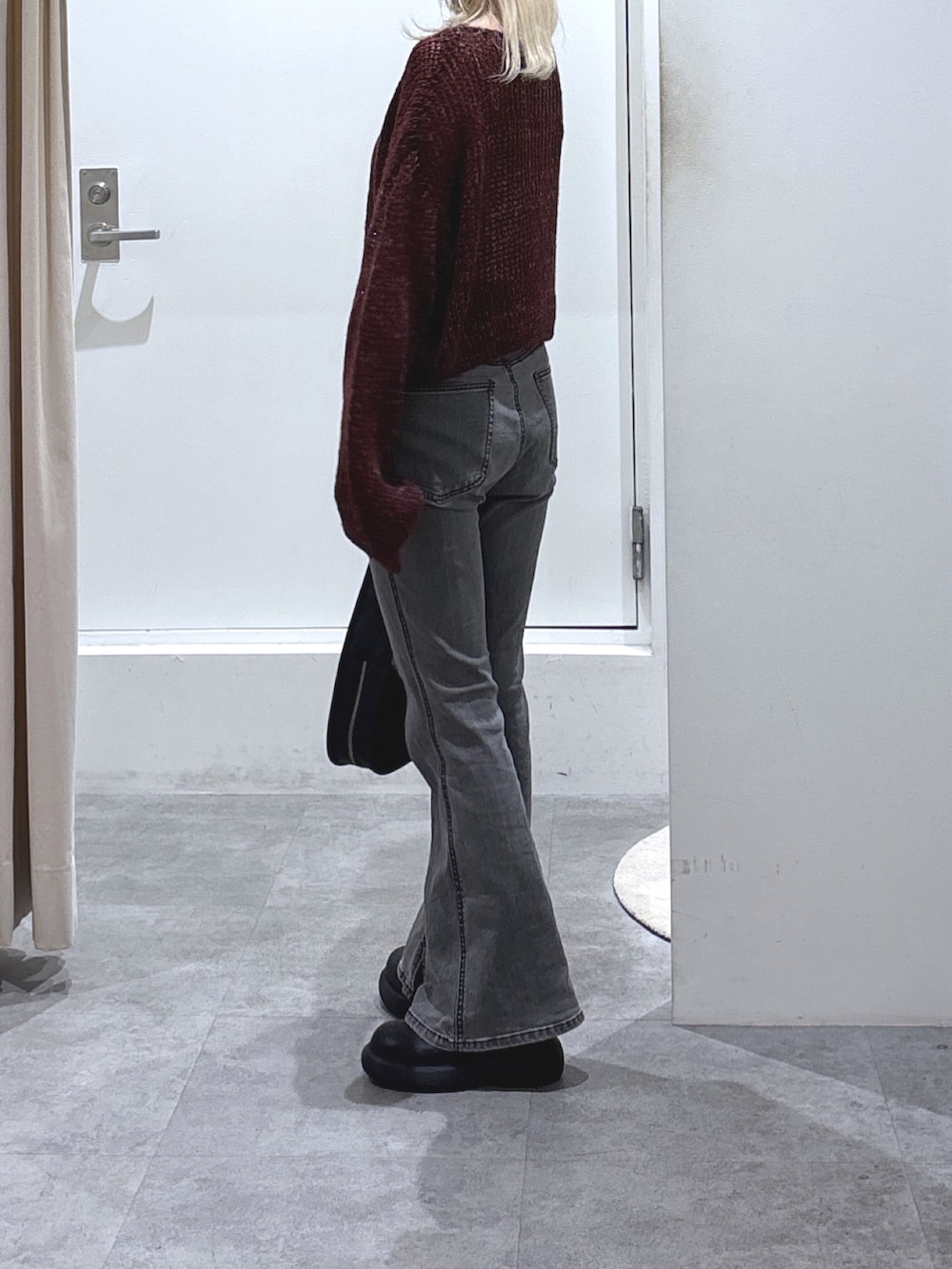 レッド系のニット/セーター、ブラック系のデニムパンツを着用したレディースの秋コーディネートの2枚目の写真