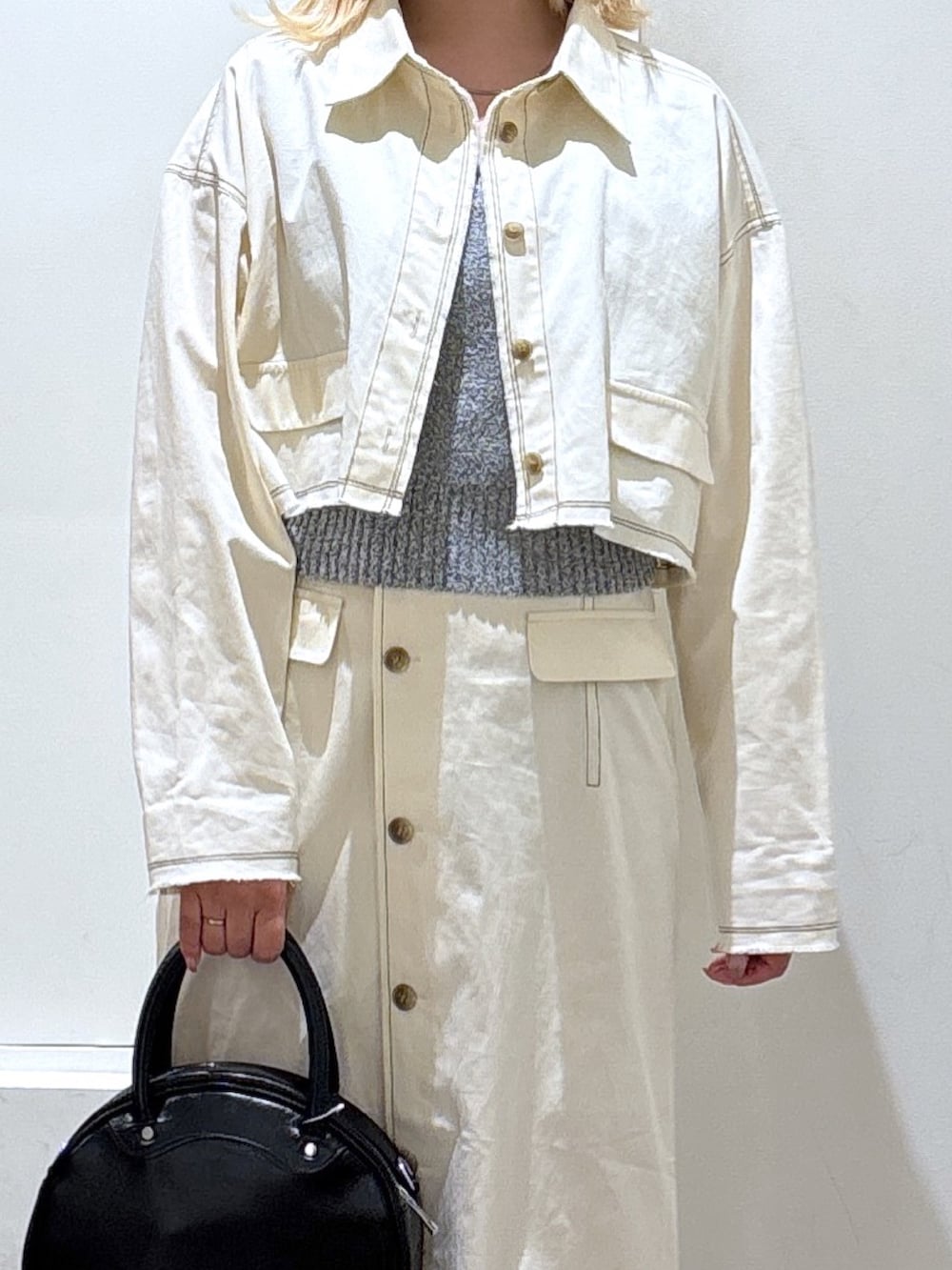 ホワイト系のブルゾン、ホワイト系のスカート、グレー系のベストを着用したレディースの春コーディネートの2枚目の写真