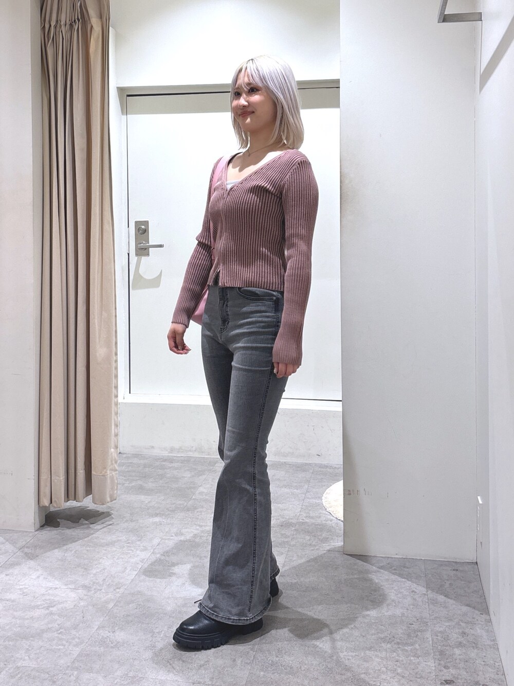 ピンク系のニット/セーター、ブラック系のデニムパンツ、ピンク系のショルダーバッグを着用したレディースの冬コーディネートの2枚目の写真