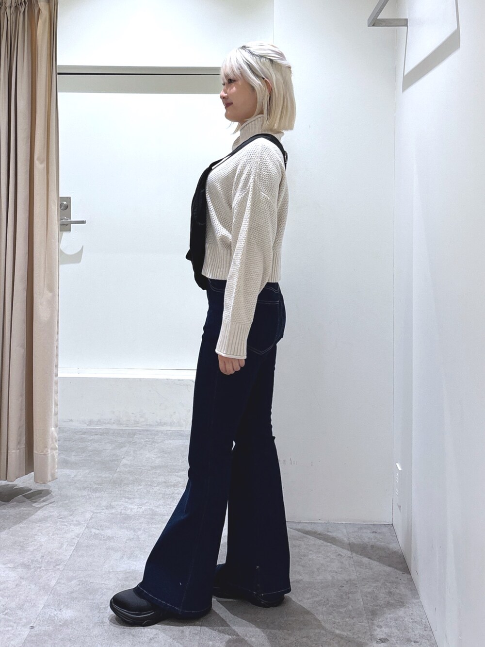 ブラック系のショルダーバッグ、ブルー系のデニムパンツ、ホワイト系のニット/セーターを着用したレディースの冬コーディネートの3枚目の写真