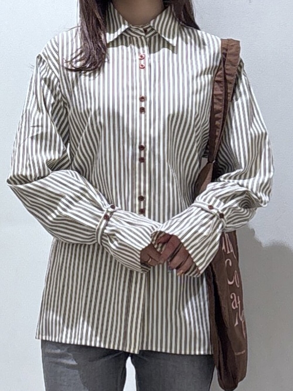 ブラウン系のシャツ/ブラウス、ブラック系のデニムパンツ、ブラウン系のトートバッグを着用したレディースの冬コーディネートの2枚目の写真