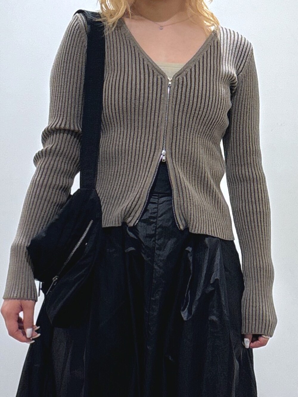 グリーン系のニット/セーター、ブラック系のスカート、ブラック系のブーツを着用したレディースの秋コーディネートの2枚目の写真