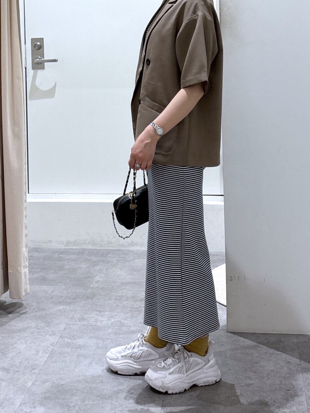 ブルー系のワンピース、ブラウン系のテーラードジャケット、ブラック系のショルダーバッグを着用したレディースの春コーディネートの3枚目の写真