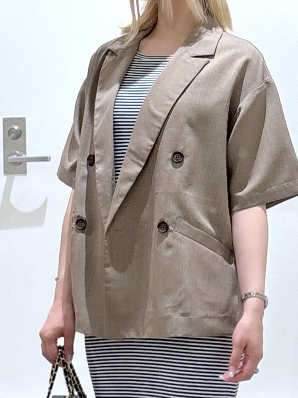 ブルー系のワンピース、ブラウン系のテーラードジャケット、ブラック系のショルダーバッグを着用したレディースの春コーディネートの2枚目の写真