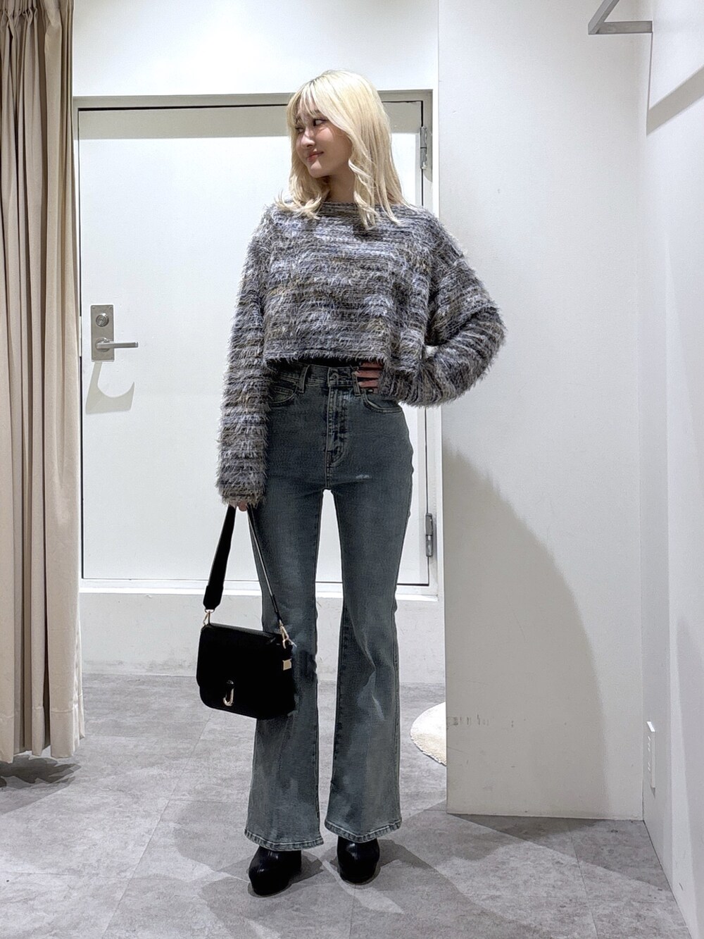 グレー系のニット/セーター、ブルー系のデニムパンツ、ブラック系のハンドバッグを着用したレディースの秋コーディネートの2枚目の写真