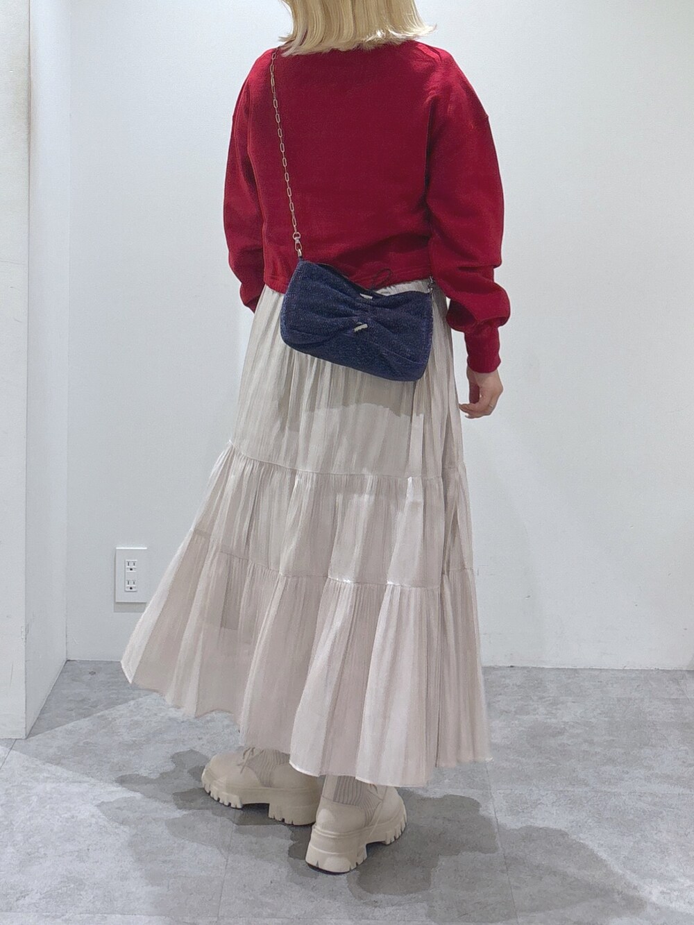 レッド系のTシャツ/カットソー、ホワイト系のスカート、ホワイト系のブーツを着用したレディースの秋コーディネートの4枚目の写真