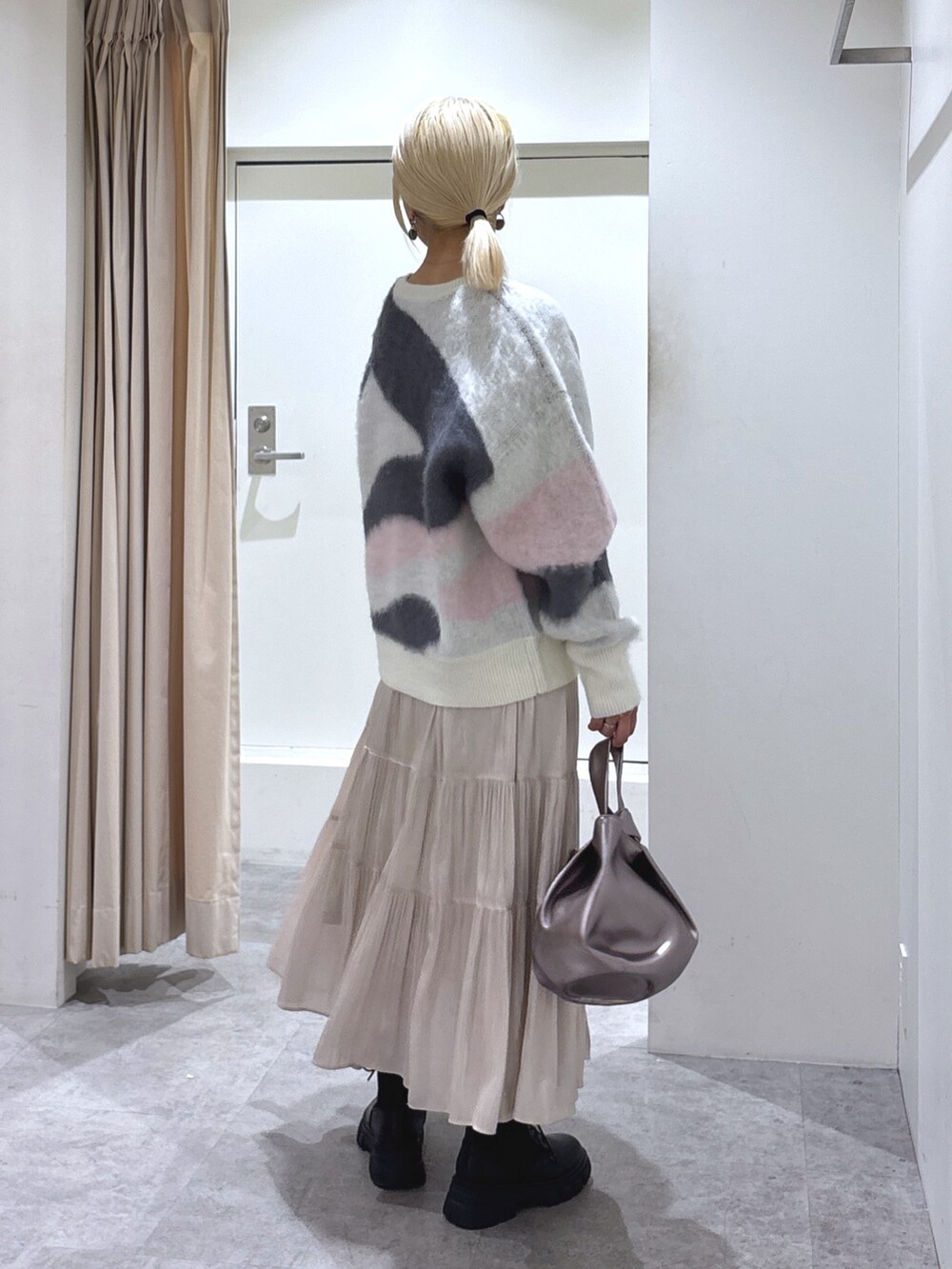 ホワイト系のニット/セーター、ホワイト系のスカート、ブラック系のブーツを着用したレディースの冬コーディネートの4枚目の写真
